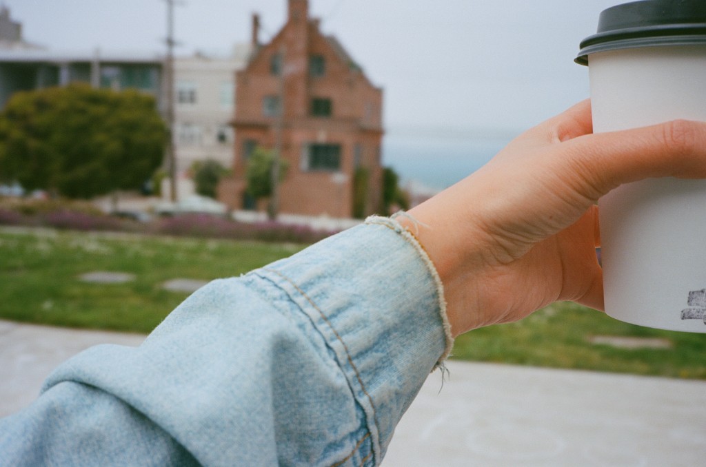 Hand holding a coffee cup near the water